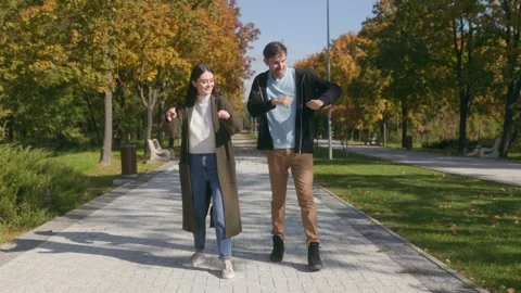 Couple in Casual Fall Clothes Dancing Happily in a Park Pathway Stock Footage 303991873