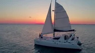 Couple On Catamaran At Sunset By Aerial Drone Stock Footage