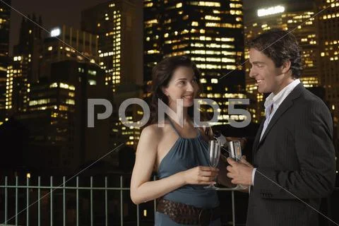 Couple With champagne Flutes Against Cityscape At Night Stock Photos