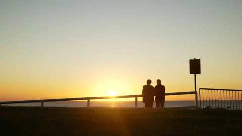 A couple chat on a cliff edge whilst sun rises 6K Video stock 307155232
