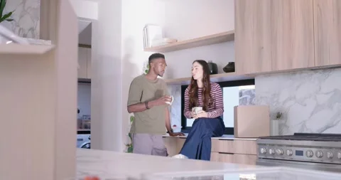 Couple chatting, sipping mugs, clinking cups and laughing amid unpacking boxes Stock Footage 337745244