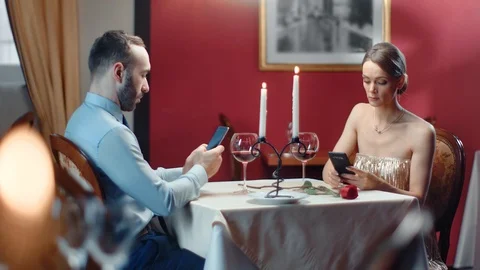 Couple chatting use smartphone during boring romantic date. Medium shot on RED Видео 124525792