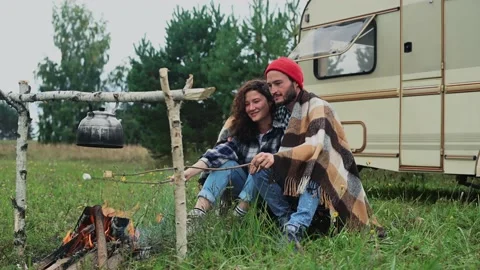 Couple in a checkered plaid roasting marshmallows on fire near the trailer home. Stockbeeldmateriaal 152183148