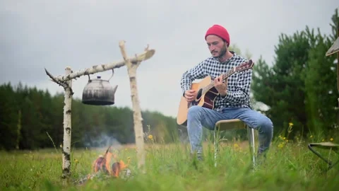 Couple in a checkered plaid roasting marshmallows on fire near the trailer home. 库存影片 170675941