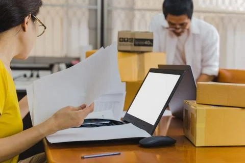 Couple checking document with open laptop and parcels on table. Stockfoto's