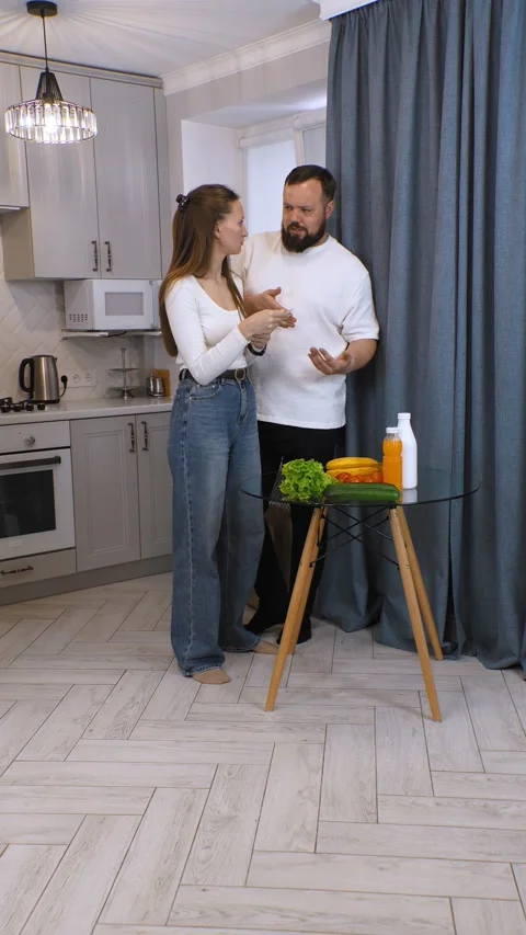 Couple checking grocery receipt and comparing with food items in kitchen Stock Footage 320493386