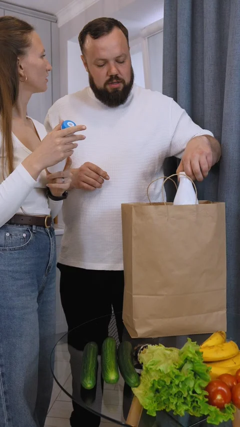 Couple checking grocery receipt and comparing with food items in kitchen Video stock 320501068