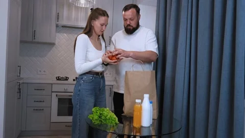 Couple checking grocery receipts and discussing nutrition in kitchen Stock Footage 320493202