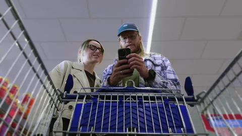 Couple checking shopping list on smartphone in supermarket Stock Footage 336611612