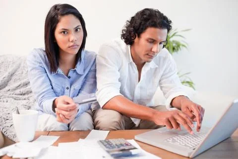 Couple checking their bank accounts online in the living room Stock Photos