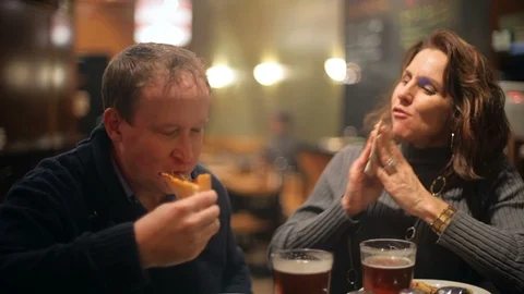 A couple cheering their beers over pizza in the city at night Stock Footage 98379742