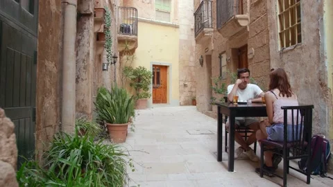 Couple Chilling And Drinking Beer On Table In Historic Street In Birgu, Malta Stock Footage 156948905