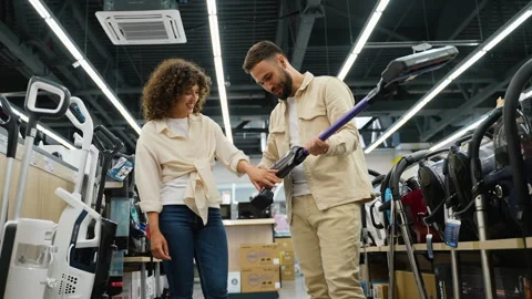 Couple choosing cordless vacuum cleaner in electronics store Stock Footage 317732953