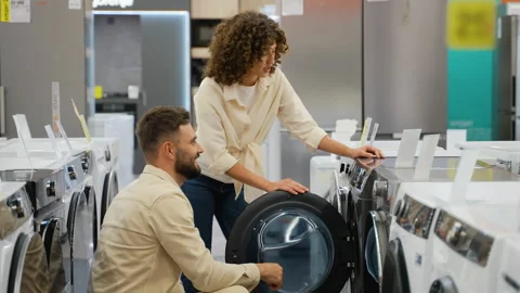 Couple choosing discounted washing machine in electronics store Stock Footage 317723370