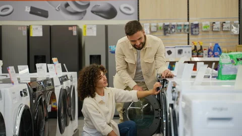 Couple choosing discounted washing machine in electronics store Stock Footage 317728504