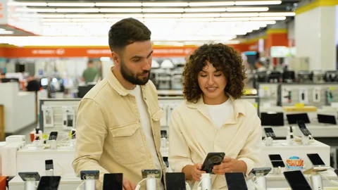 Couple choosing smartphone in electronics store Stock Footage 317730923