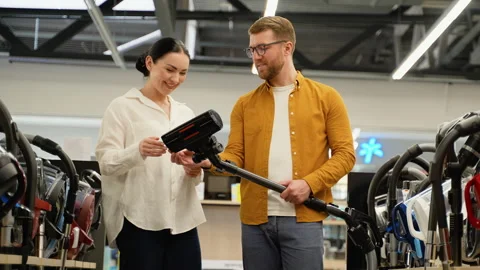 Couple choosing vacuum cleaner in an electronics tech store Stock Footage 279637613