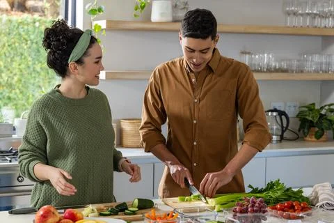 Couple chopping celery and talking at kitchen counter with cutting board, knife, Stock Photos
