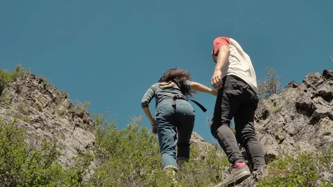 Couple climbing mountain range, hand reaches out to help,slow motion Stockbeeldmateriaal 92840501