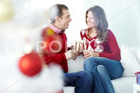 Couple clinking champagne flutes at home at Christmas Stock Photos