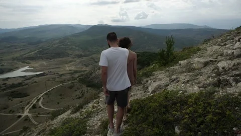 The couple come down from the mountain holding on to each other Stock Footage 136743959