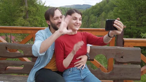 Couple communicates via video calling on a mobile phone. Man hugging woman. Stockbeeldmateriaal 130567912