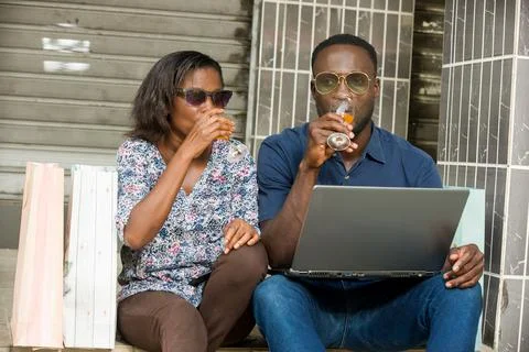 Couple connected to a computer and drinking fresh drink Stock Photos