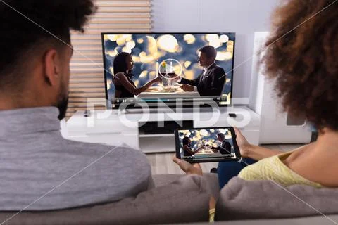 Couple Connecting Television Through WiFi On Digital Tablet Stock Photos