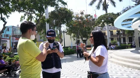 A couple consulting a guide about instructions in the plaza de huacho, lima, per Stock Footage 196728126