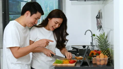 Couple cooking and preparing vegetables according to a recipe on a tablet Stock Footage 170709273