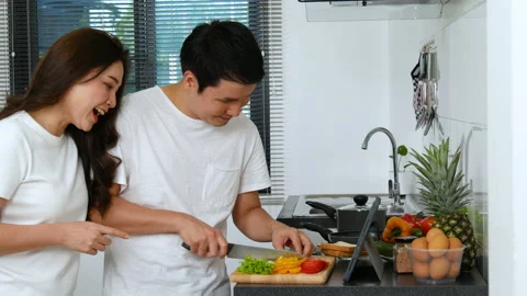 Couple cooking and preparing vegetables according to a recipe on a tablet Stock Footage 170709369