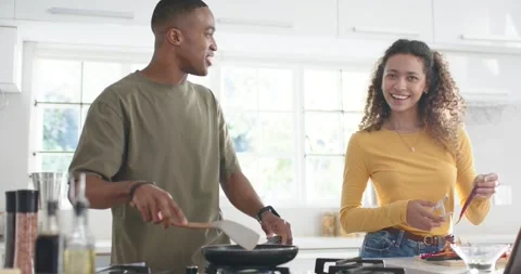 Couple cooking dinner in kitchen, following tablet while man flipping pan and Stock Footage 337286942