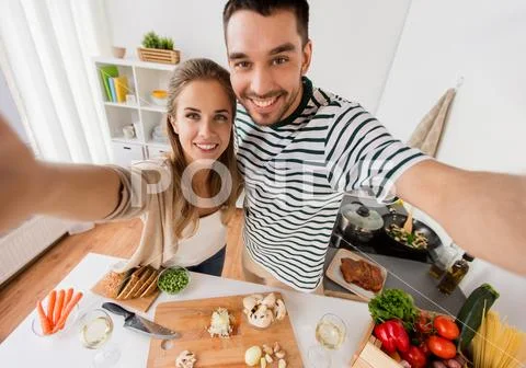 Couple cooking food and taking selfie at kitchen Stock Photos