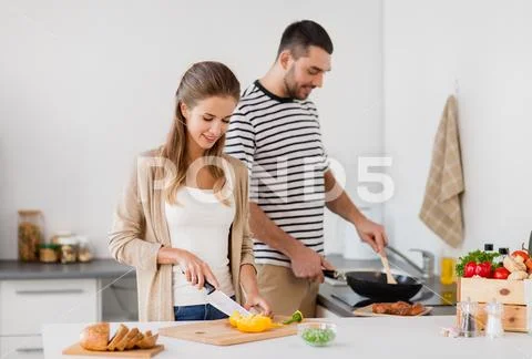Couple cooking food at home kitchen Stock Photos