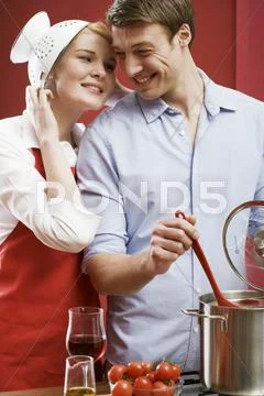 Couple cooking pasta with tomatoes Stock Photos