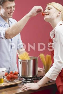 Couple cooking spaghetti with tomatoes Stock Photos