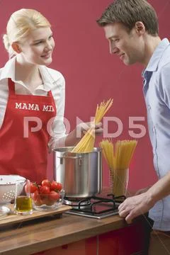 Couple cooking spaghetti with tomatoes Stock Photos