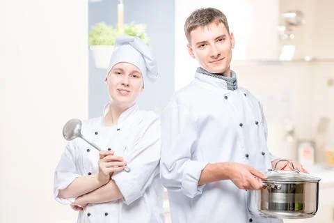 Couple of cooks in the kitchen Stock Photos