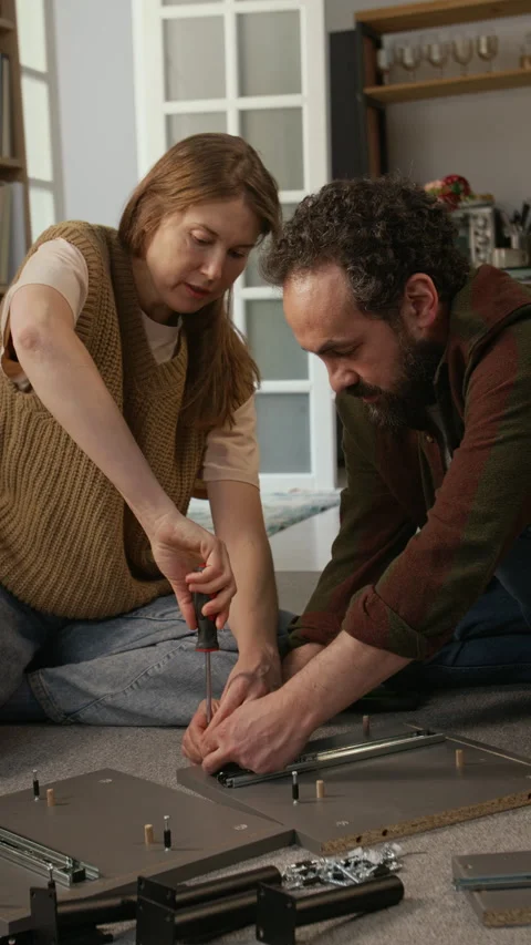 Couple Cooperating while Assembling Flatpack Furniture Piece at Home Stock Footage 330511652