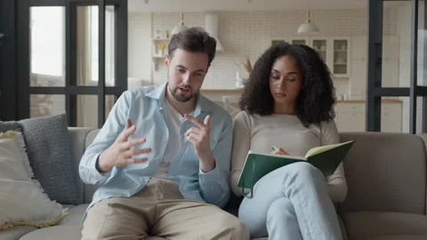 Couple On Couch, Man Explains While Woman Writes Notes In Notebook Stock Footage 306698595