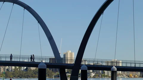 A couple cross bridge with double span over river. Tall buildings on far side Stock-Footage 204054454
