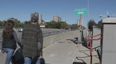 Couple crossing bridge over river along busy road Stock Footage 68446771