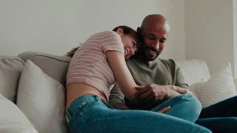 Couple Cuddle On Sofa At Home Stock Photos