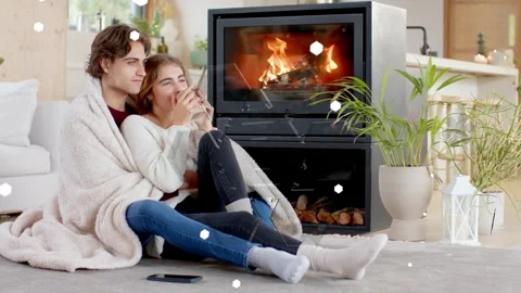 Couple cuddling under throw by stove phone buzzing, woman with mug, shapes Stock Footage 339448499