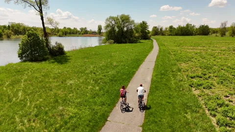 Couple Cycling Paved Path Along Waterway, St Lawrence Parks, Ontario Stock Footage 337585600