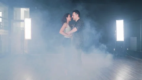 A couple dances in a dance studio filled with smoke Stock Footage 107427724