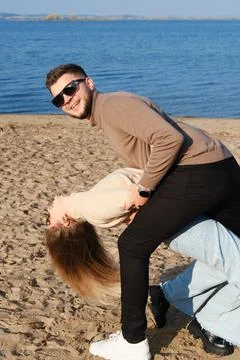 The couple is dancing, having fun and fooling around on the beach. A young be Stock Photos
