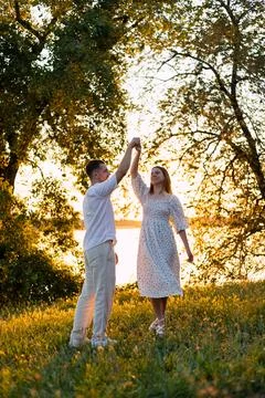 Couple dancing joyfully in a sun-drenched meadow during golden hour Stock Photos
