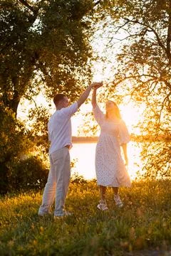 Couple dancing joyfully in a sun-drenched meadow at golden hour Stock Photos