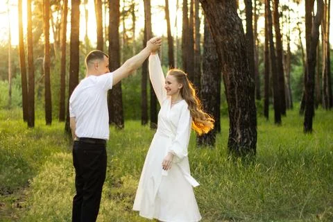 Couple dancing joyfully in a sun-drenched pine forest at golden hour Stock Photos
